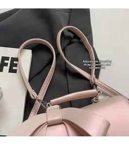 Detail of pink crossbody bag with large bow and adjustable silver metal strap hooks