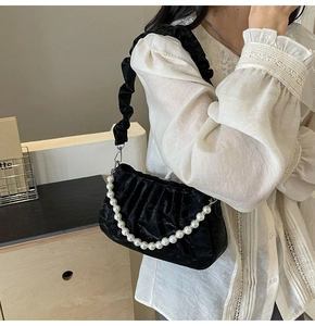 Vue macro du sac plissé en velours noir avec détail de chaîne élégante en perles