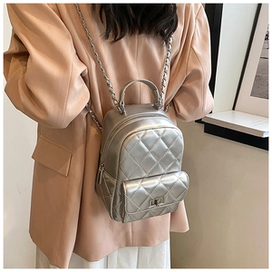 Detailed back view of a silver quilted mini backpack with chain straps on a model