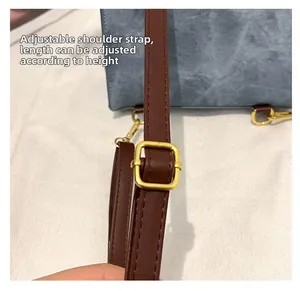 Detail of adjustable dark brown shoulder strap with gold buckle on a blue textured tote bag