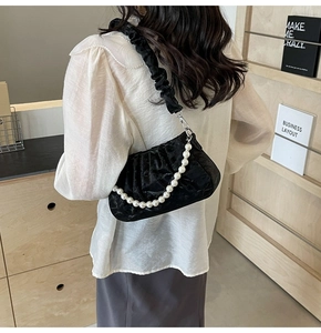 Détail du sac plissé noir avec chaîne en perles et texture de tissu élégante et souple