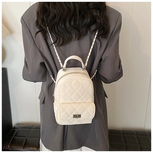 Detail of a beige quilted mini backpack with leather chain straps and metal twist-lock