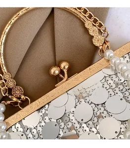 Nahaufnahme des goldenen gravierten Rahmens und der silbernen Pailletten einer Abendtasche