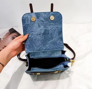 Detail view of denim tote bag showing brown leather straps and internal zipper pocket