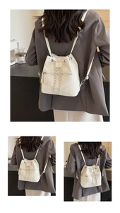 Close-up of cream bucket backpack with silver chain detail and drawstring closure
