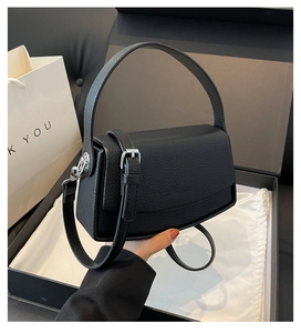 Close-up of black pebble grain leather texture and metallic buckle on a stylish handbag