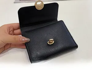 Close-up of golden metal twist lock on black litchi grain leather wallet for women