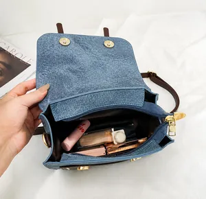 Detail of blue denim textured bag interior with magnetic clasp and makeup storage