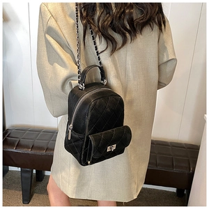 Close-up of a black quilted leather mini backpack with silver chain straps and turn-lock