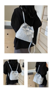 Detail view of light grey bucket backpack with pleated texture and silver chain strap