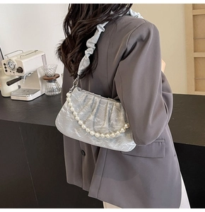 Detail of silver pleated shoulder bag featuring pearl chain strap and silk metallic texture
