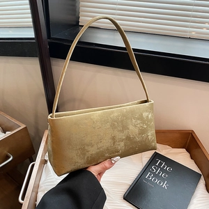Chic vintage gold rectangular underarm bag with aged texture on a wooden tray with books