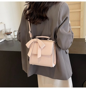Close-up of pink crossbody bag featuring a large decorative bow and matte PU leather texture