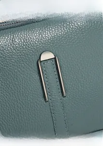 Detail of teal pebble leather texture and gunmetal hardware on a shoulder bag