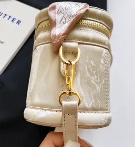 Macro shot of cream white bucket bag with gold hardware and pink heart pattern scarf