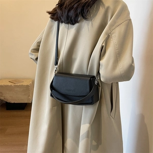 Minimalist black lychee leather crossbody bag with a top handle and shoulder strap