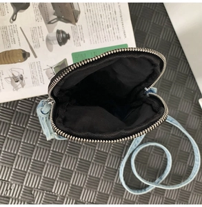 Dettaglio della borsa a tracolla in denim azzurro con fodera interna nera e chiusura a zip