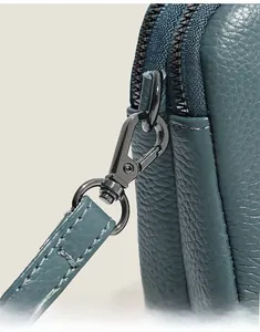 Detail of cross-body bag with double zippers and metallic swivel hooks on pebble leather