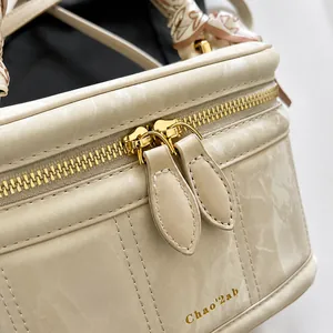 Close-up of marble texture bag with dual gold zippers and silk scarf handle detail