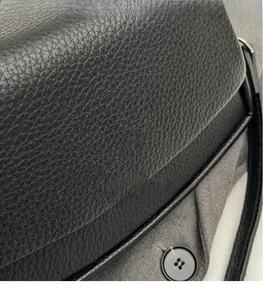 Close-up of black lychee grain leather handbag showing texture and round button detail