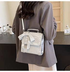 Close-up of silver crossbody bag with metallic wrinkled texture and large bow detail