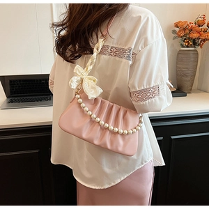 Detailaufnahme der rosa Plissee-Schultertasche mit Perlenkette und Satinschleife