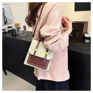 Side view of a vintage beige and brown flap crossbody bag styled with a pink blazer