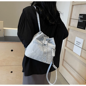 Detail of a light blue pleated bucket bag showing drawstring closure and chain strap