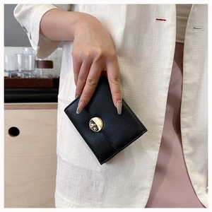 Detailed view of women's black pebble leather wallet with a golden twist lock closure