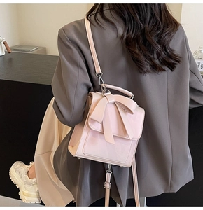 Light pink handbag with bow design shown in a minimalist business-style setting