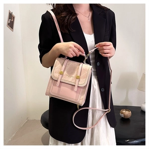 Detailed view of pink tote with mixed leather textures and decorative metal buckles