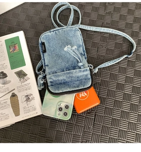 Dettaglio borsa porta cellulare in denim blu con effetto usurato e tracolla regolabile