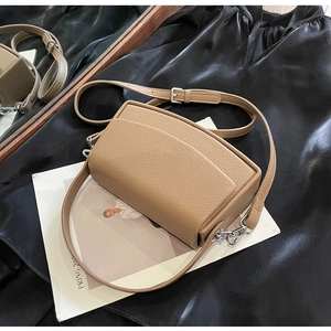Close-up of khaki pebbled leather texture and silver metal hardware on a square bag