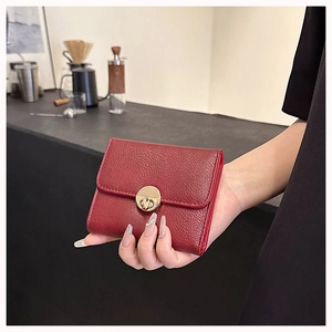 Deep red lychee texture wallet detail with elegant gold metal twist lock closure