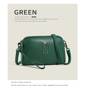 Close-up of green pebble leather crossbody bag with metal zipper and strap details