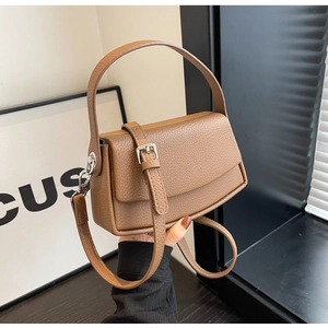 Close-up of brown lychee texture leather handbag with silver hardware and strap