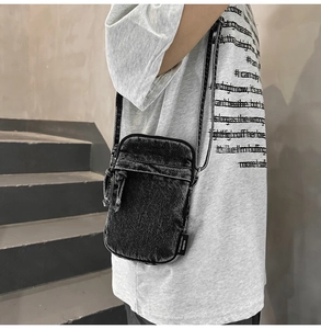 Dettaglio di una borsa a tracolla in denim per cellulare con etichetta tessuta O.A.BAG