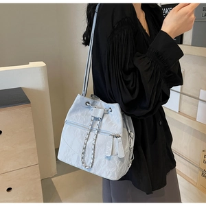 Close-up of light blue leather bucket bag featuring silver chains and zipper detail