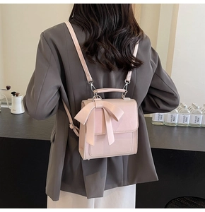 Detailed view of a pink bow backpack with silver hardware on a female model