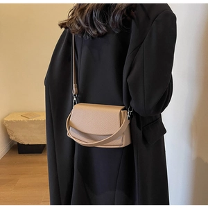 Detailed view of the dark beige lychee pattern leather shoulder bag on a model