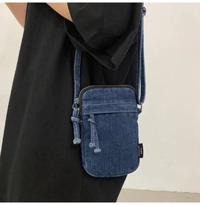 Detailansicht der blauen Denim-Umhängetasche mit weißen Nähten und Kordelzug-Detail