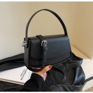 Detail of black litchi grain leather shoulder bag with silver hardware and top handle