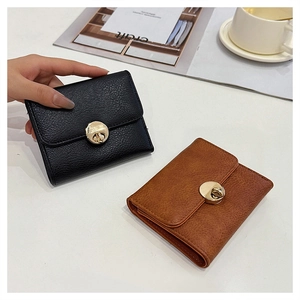 Detail of short leather wallets in black and brown with golden metal twist locks