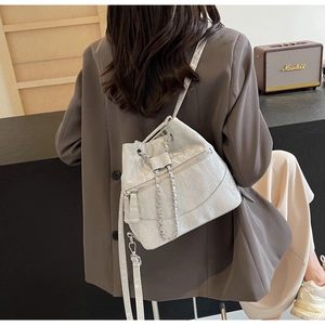 Detail of white bucket bag featuring pleated texture and elegant metal chain strap
