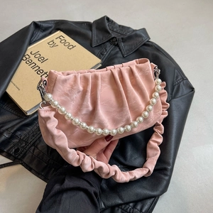 Sac nuage froncé rose avec poignée en perles et texture marbre sur une veste noire