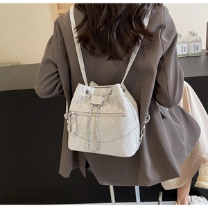 Back view of a white pearlescent bucket backpack with silver chain on model