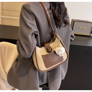 Détail du sac seau en cuir crème avec poche marron et breloque mouton en peluche