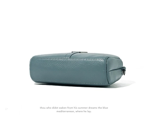 Detail view of the pebbled leather texture and side profile of the blue crossbody bag