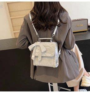 Detail of silver metallic textured mini backpack with a large decorative bow on front