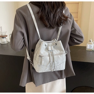 Detail view of silver drawstring bucket backpack with unique pleated texture and chain detail